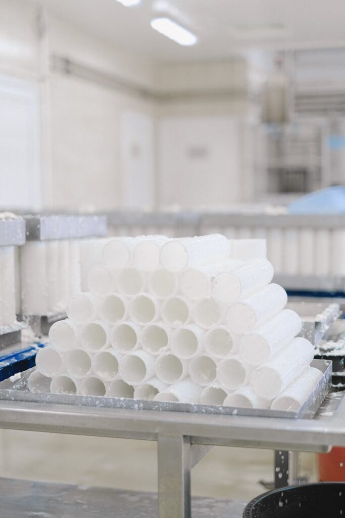 Vertical shot of neatly stacked white plastic tubes in an industrial manufacturing plant.